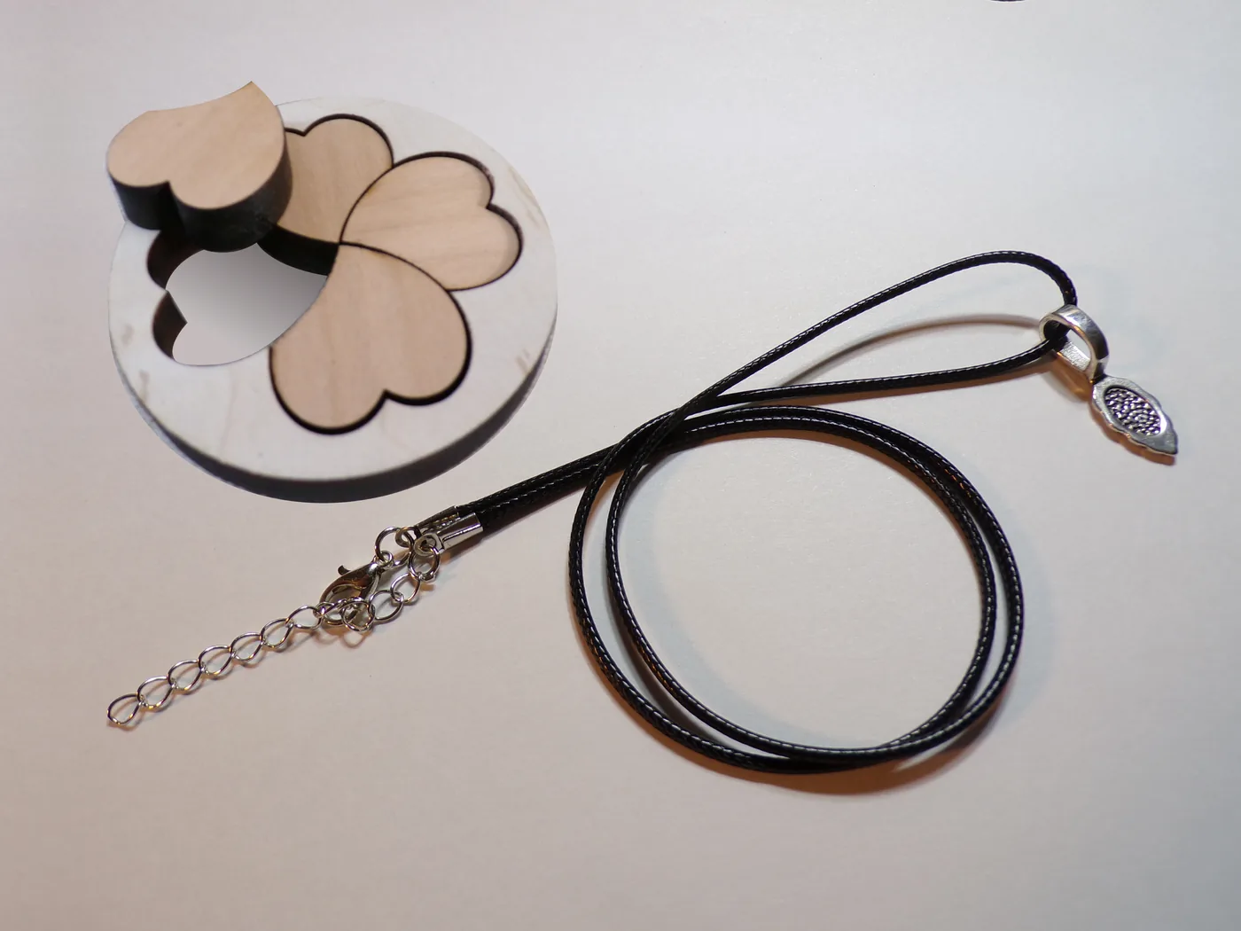Laser-cut pendant inlay beside the included leather-cord necklace, clasp and bail